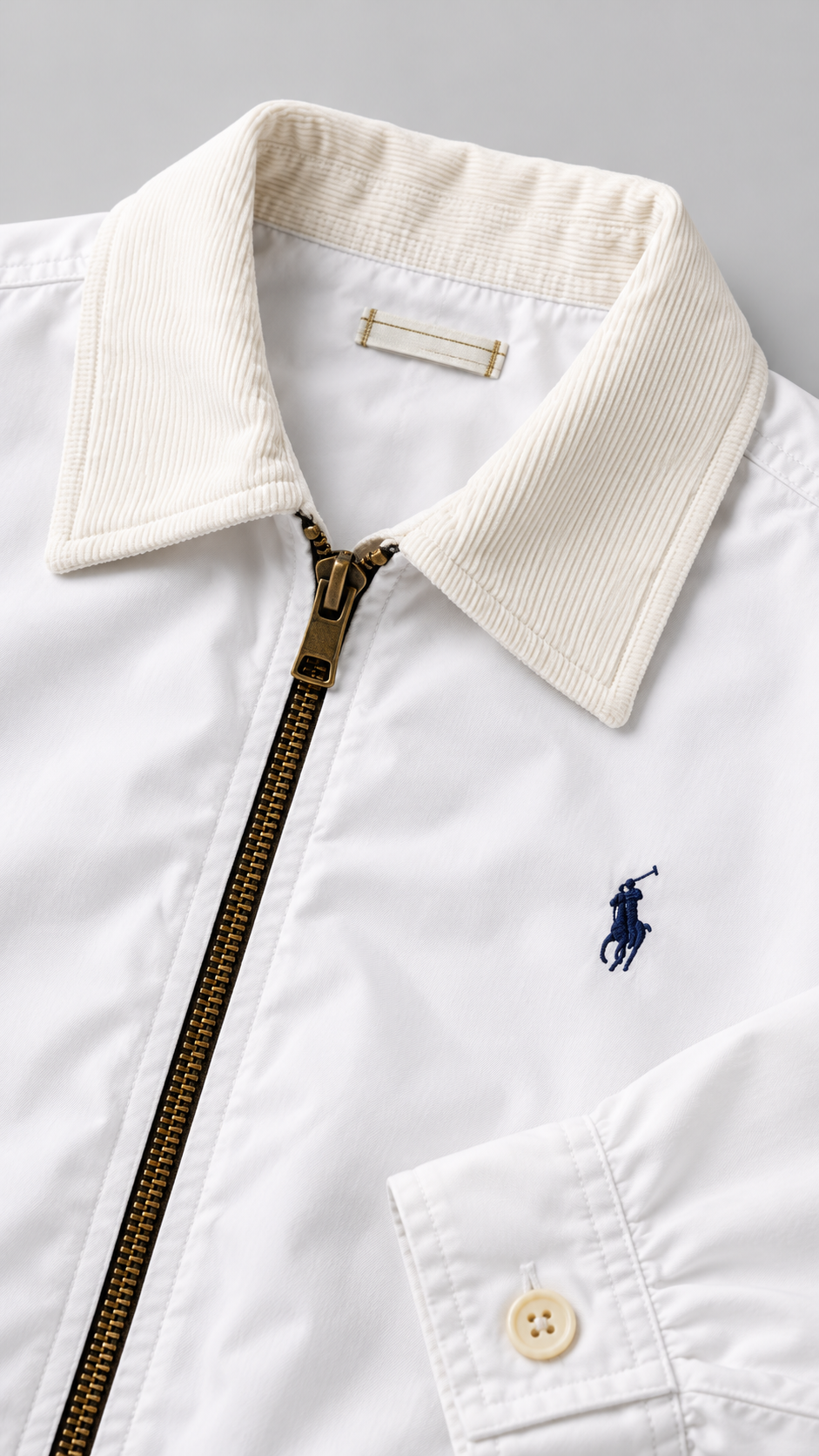 White Gold Label: editorial detail van witte stof, corduroy kraag, rits en borduurlogo